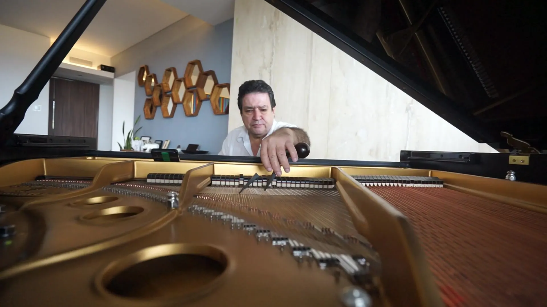 El maestro Rafael Melo trabaja en la mecánica de un piano de cola, visto desde dentro del instrumento.